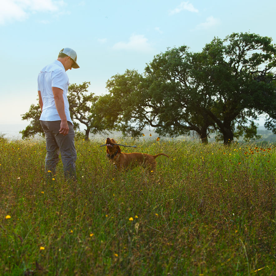 A man standing with his dog in the beautiful Texas Hill Country.